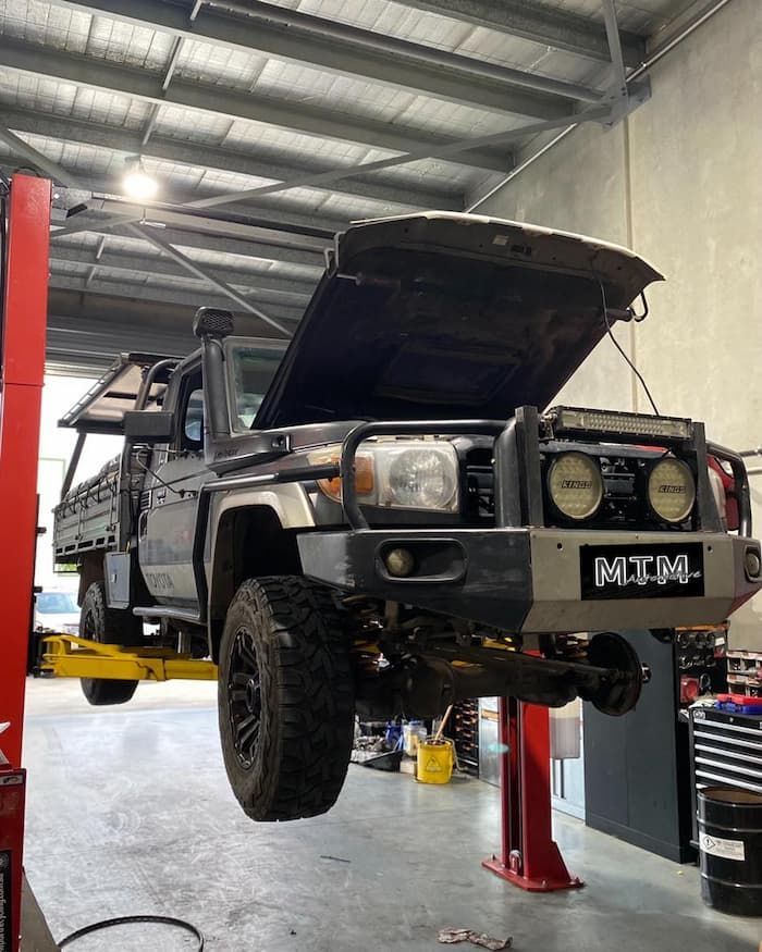 A Truck Is Sitting On A Lift In A Garage With The Hood Open — MTM Automotive in Bentley Park, QLD
