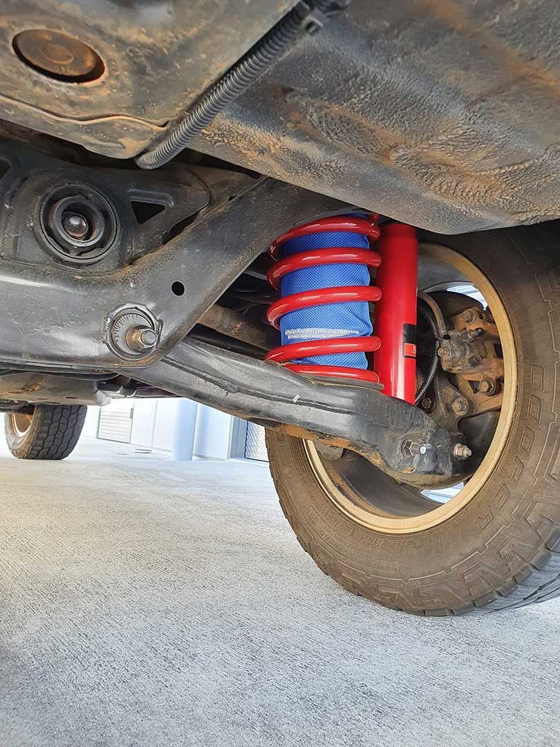 A Close Up Of The Underside Of A Car With A Red Shock Absorber — MTM Automotive in Bentley Park, QLD