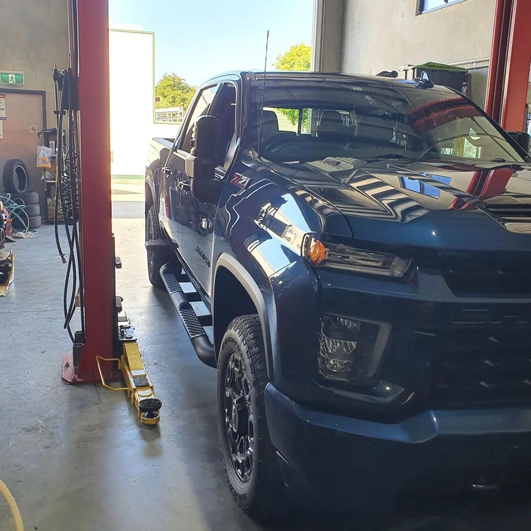 A Blue Truck Is Parked On A Lift In A Garage — MTM Automotive in Bentley Park, QLD