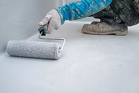 A person is painting a floor with a roller.