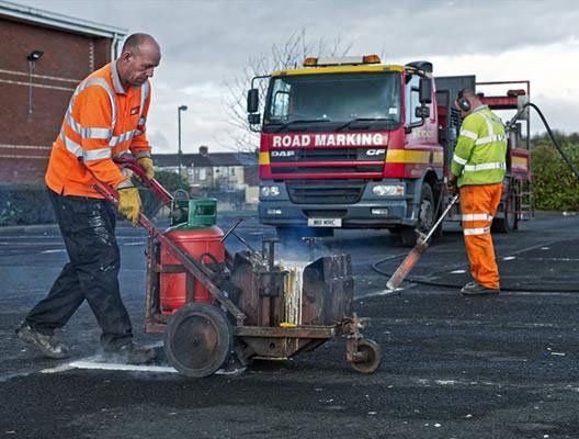 Workers adding and removing thermoplastic line markings