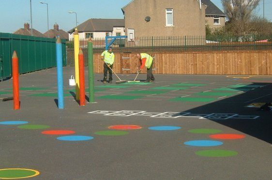 Line markers adding paint to a playground