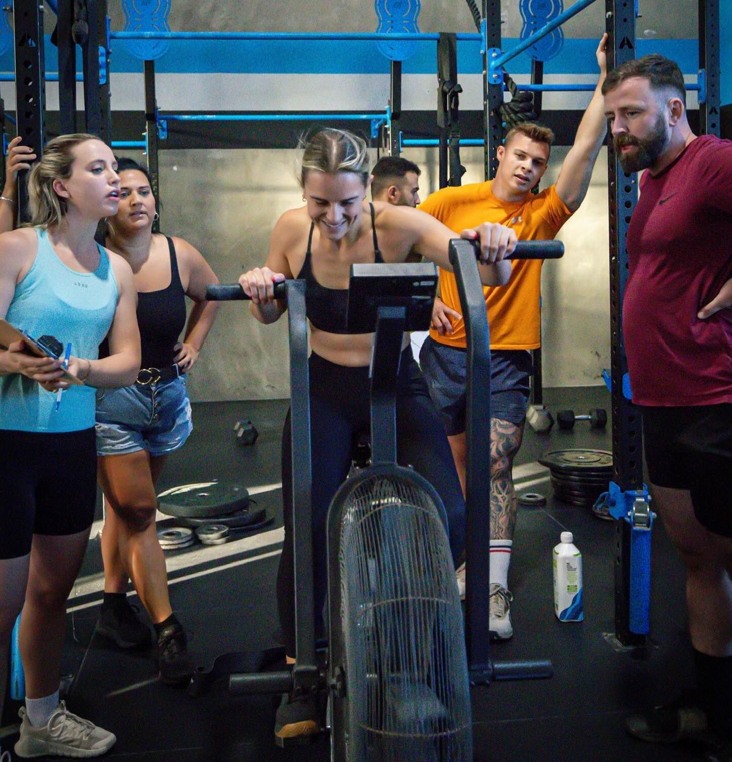 A group of people are standing around a machine in a gym