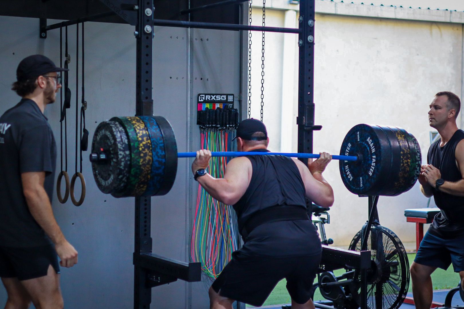 A man is squatting with a barbell in a gym.