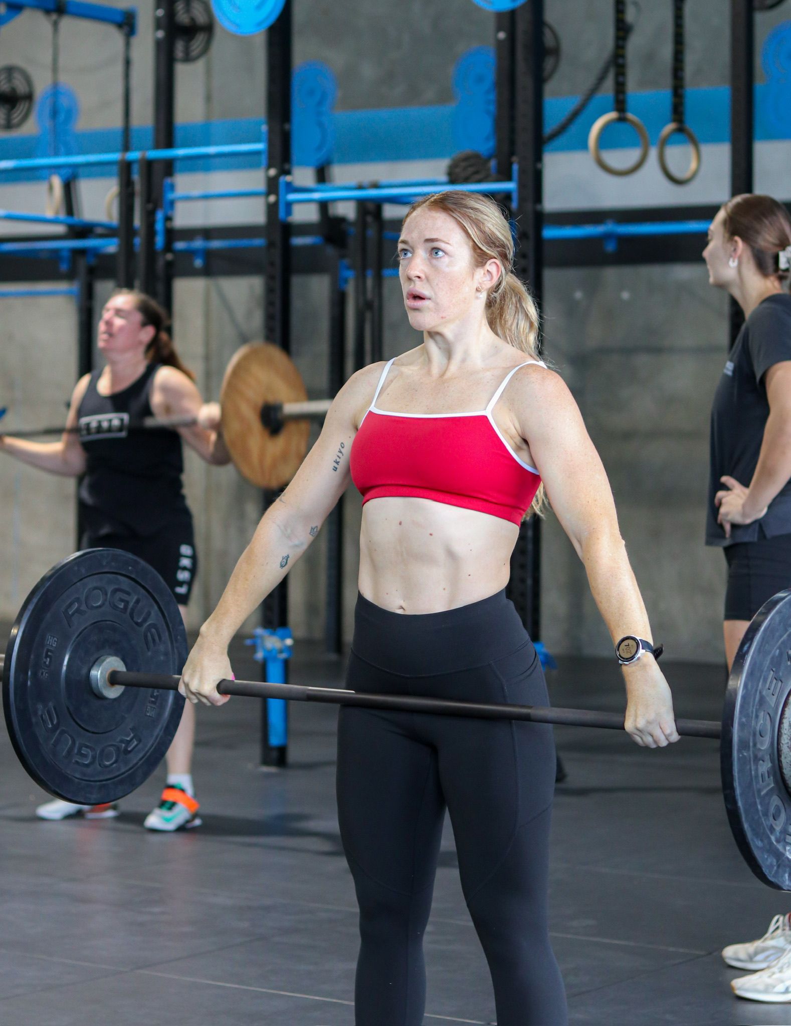 A woman is lifting a barbell in a gym.