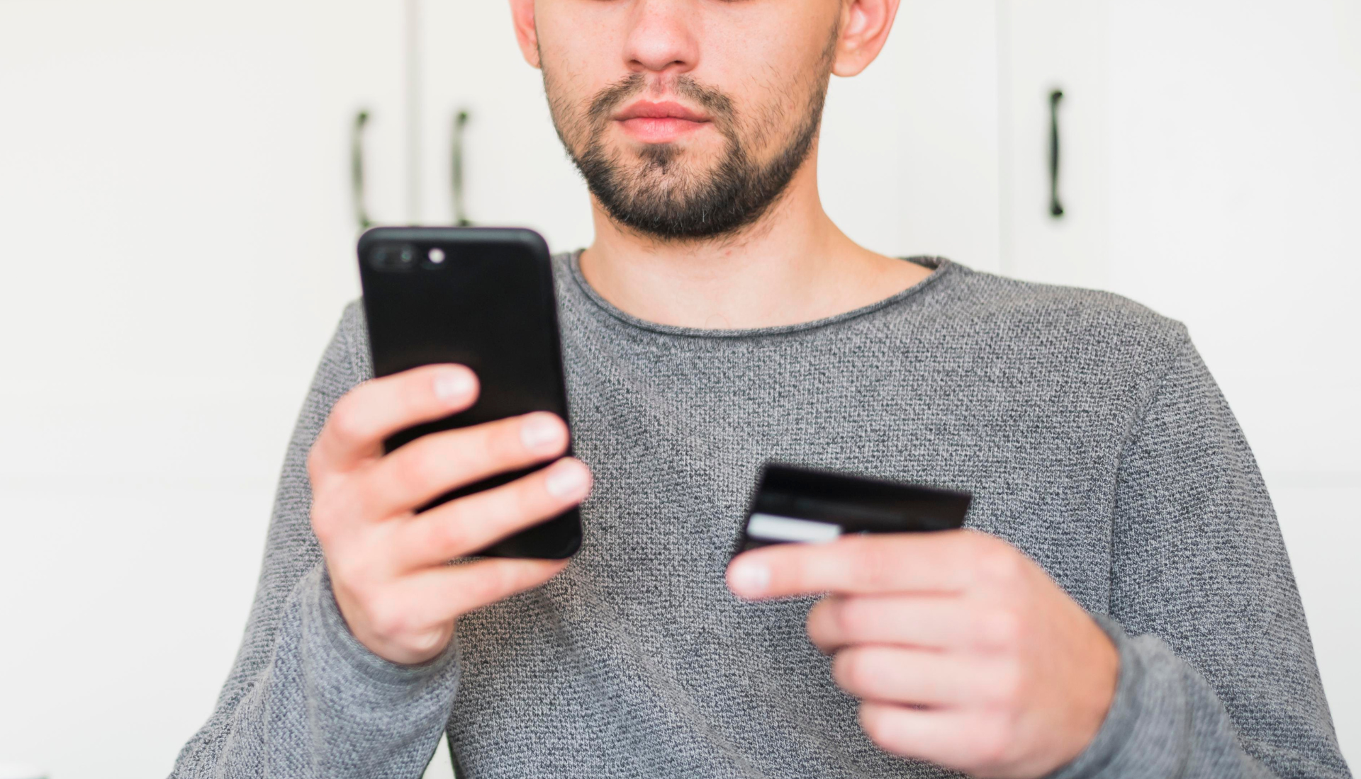 Ein Mann hält eine Kreditkarte und ein Mobiltelefon.