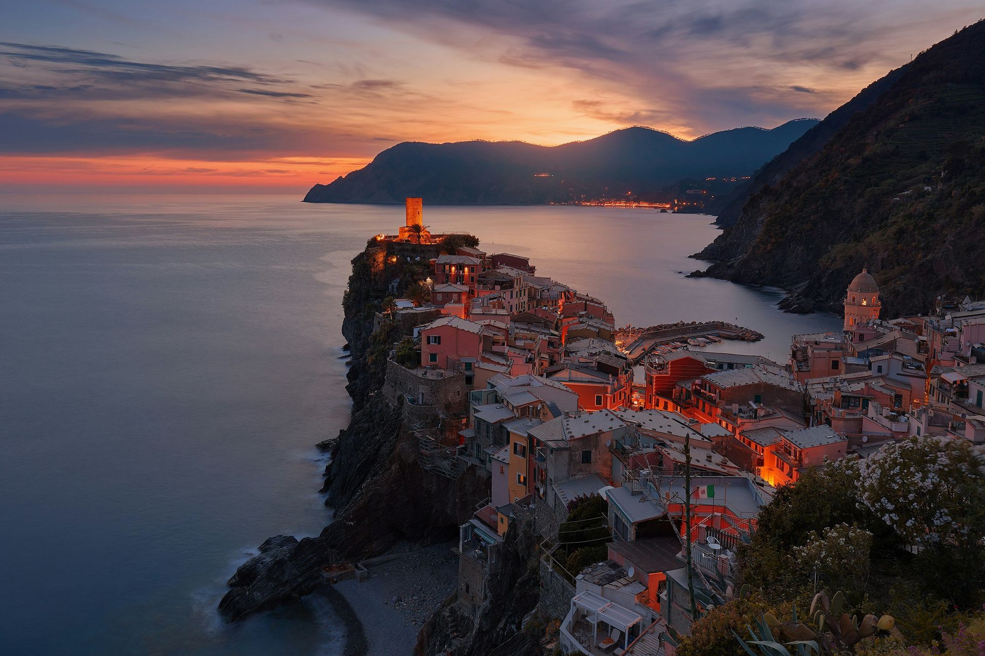 A city on a cliff overlooking the ocean at sunset