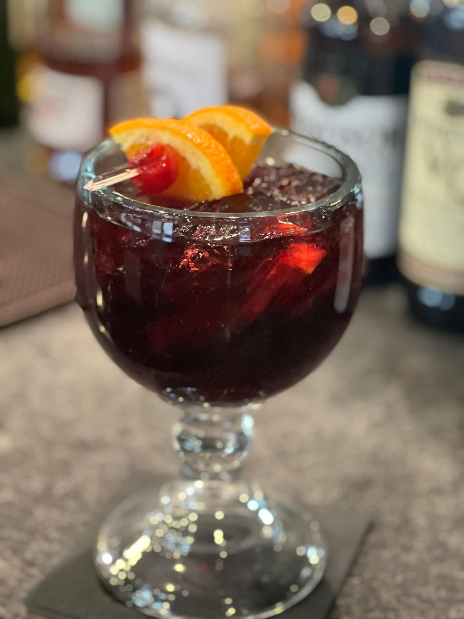 A glass of wine with a cherry and orange slice on top