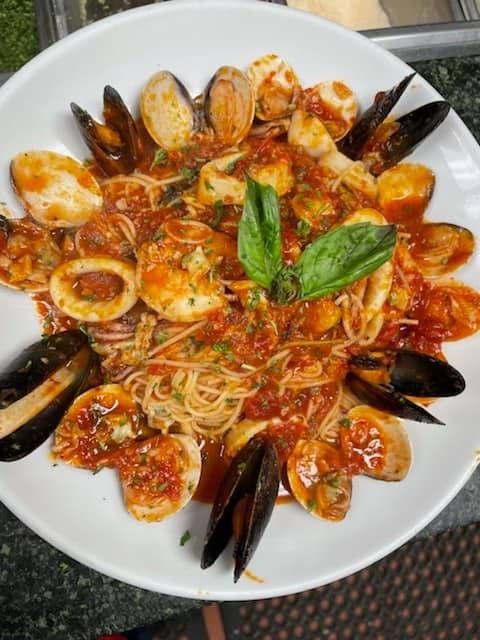 A white plate topped with spaghetti and seafood