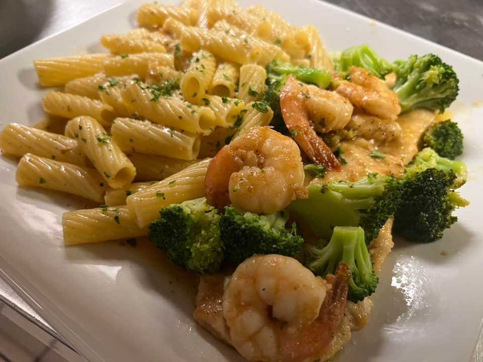 A white plate topped with pasta shrimp and broccoli