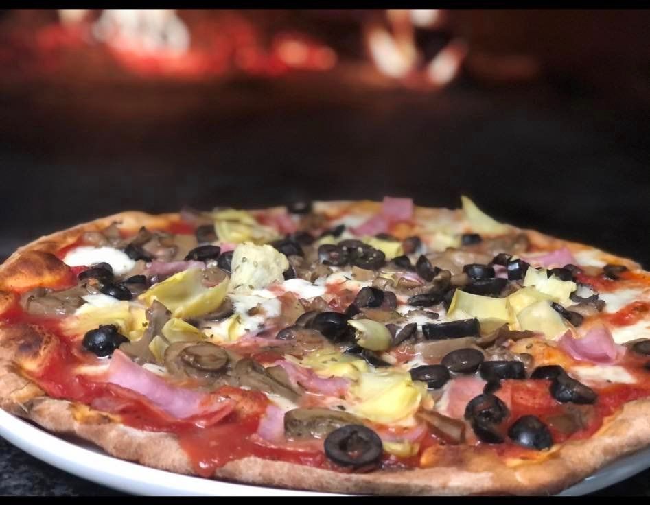 A pizza with olives and artichokes on a white plate