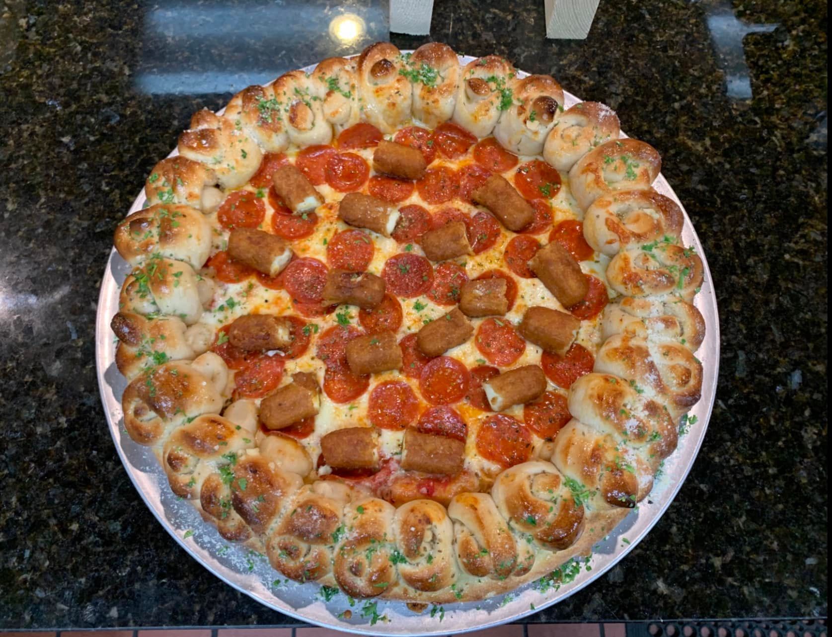 A pizza with pepperoni and sausage on a plate on a table.