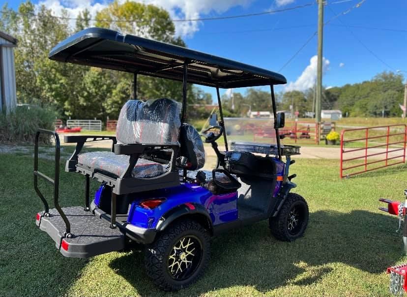 A blue golf cart is parked in a grassy field.