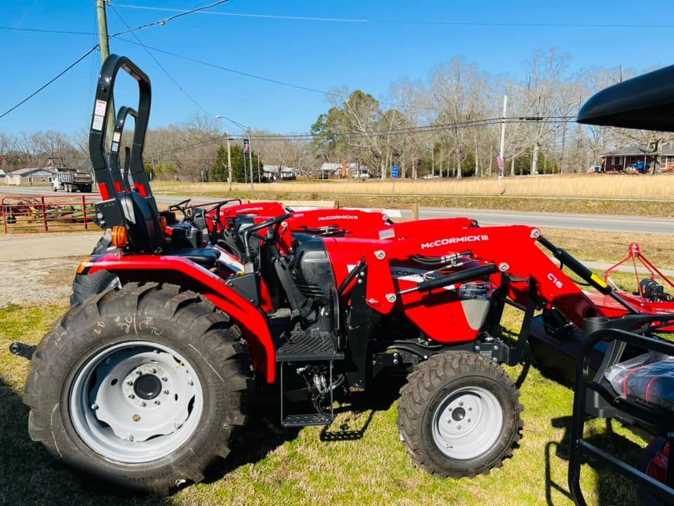 A red tractor is parked in a grassy field.