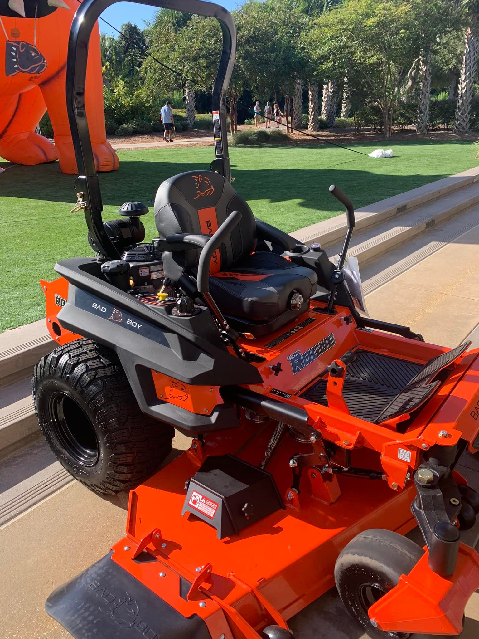 An orange lawn mower is parked on the side of the road.