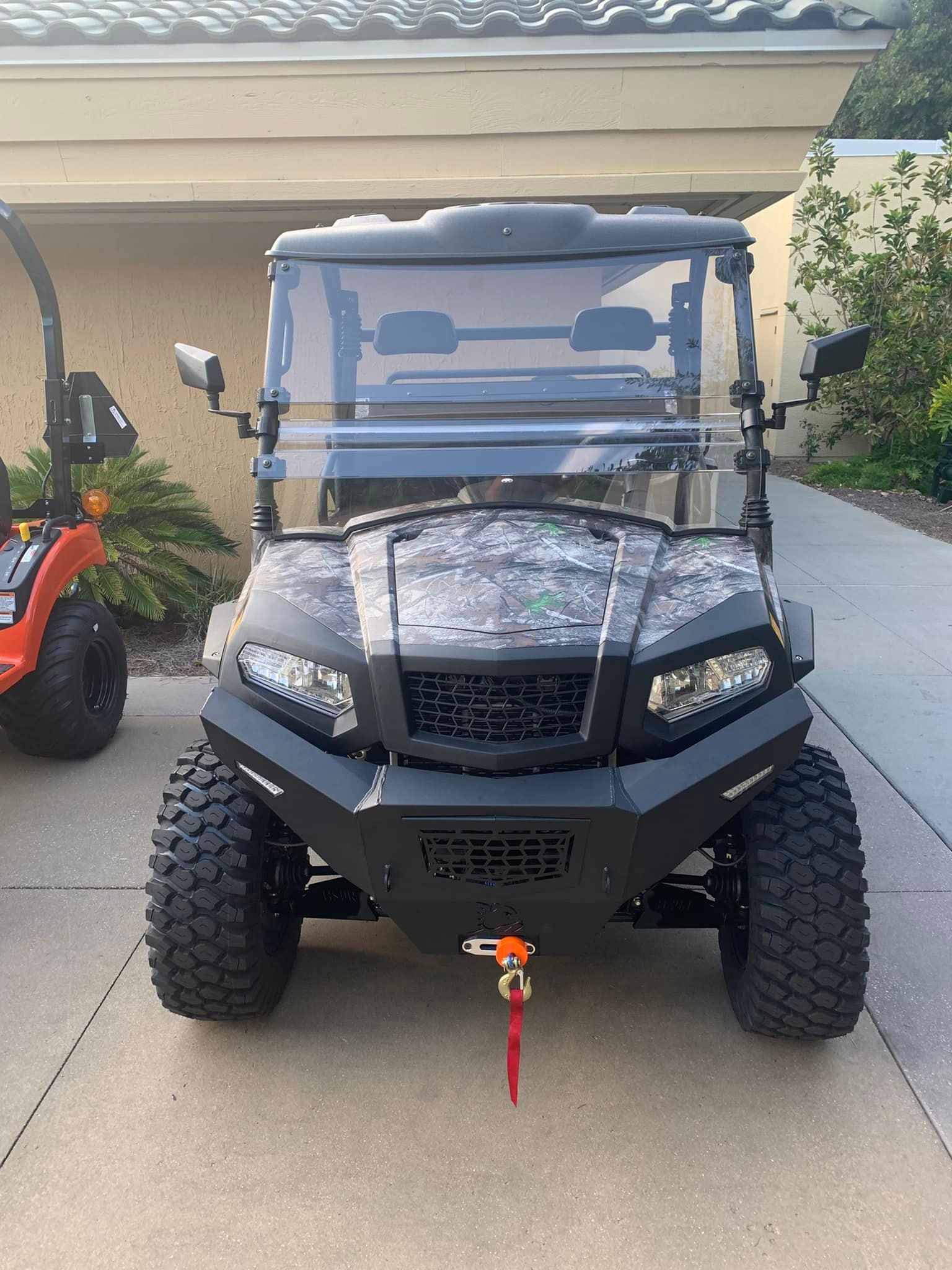 A golf cart is parked in a driveway in front of a house.