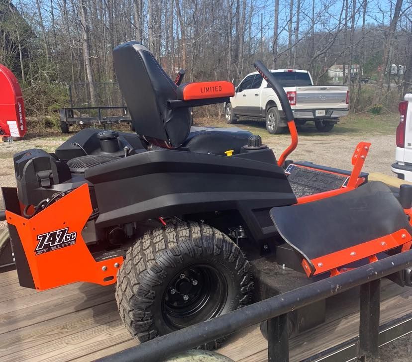 A black and orange lawn mower is parked on a trailer.