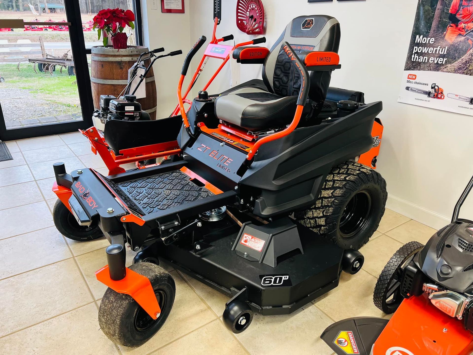 A black and orange lawn mower is parked in a room.