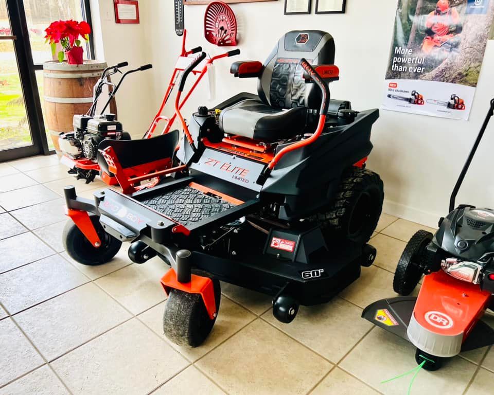 A lawn mower is sitting in a room next to another lawn mower.