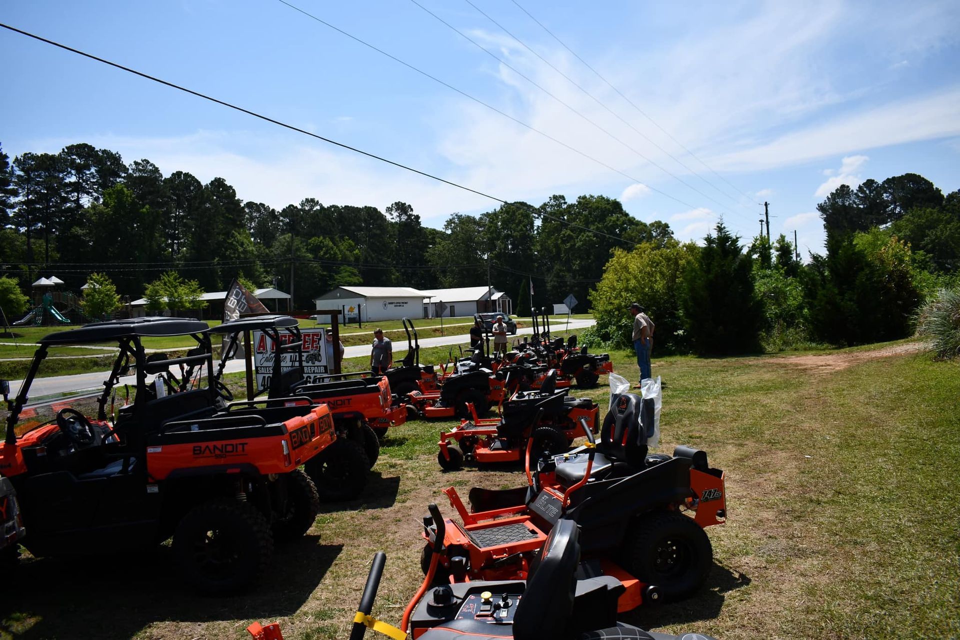 A row of lawn mowers are parked in a grassy field.
