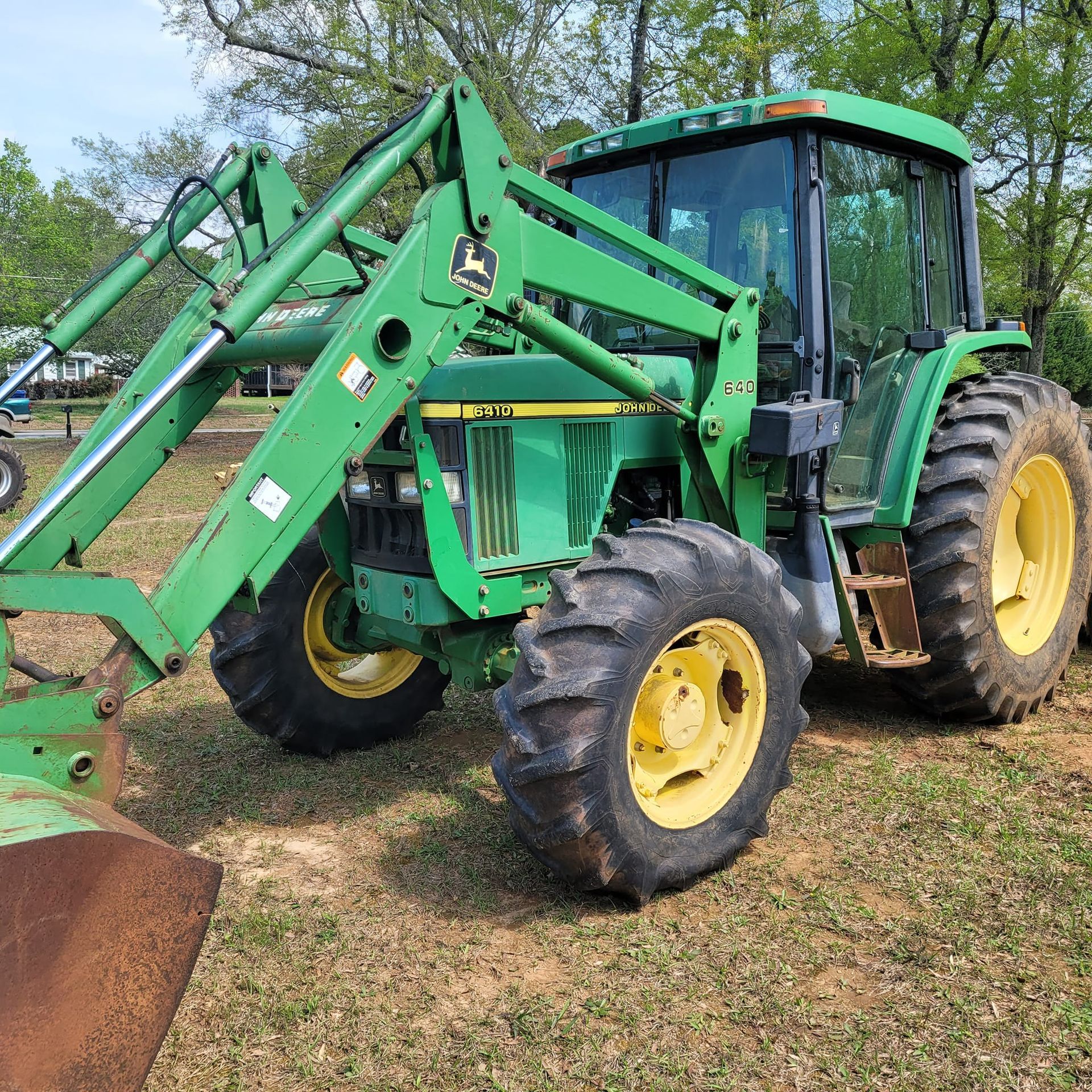A green john deere tractor is parked in a grassy field.