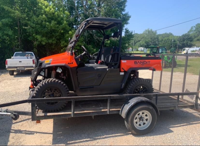 An orange atv is sitting on top of a trailer.