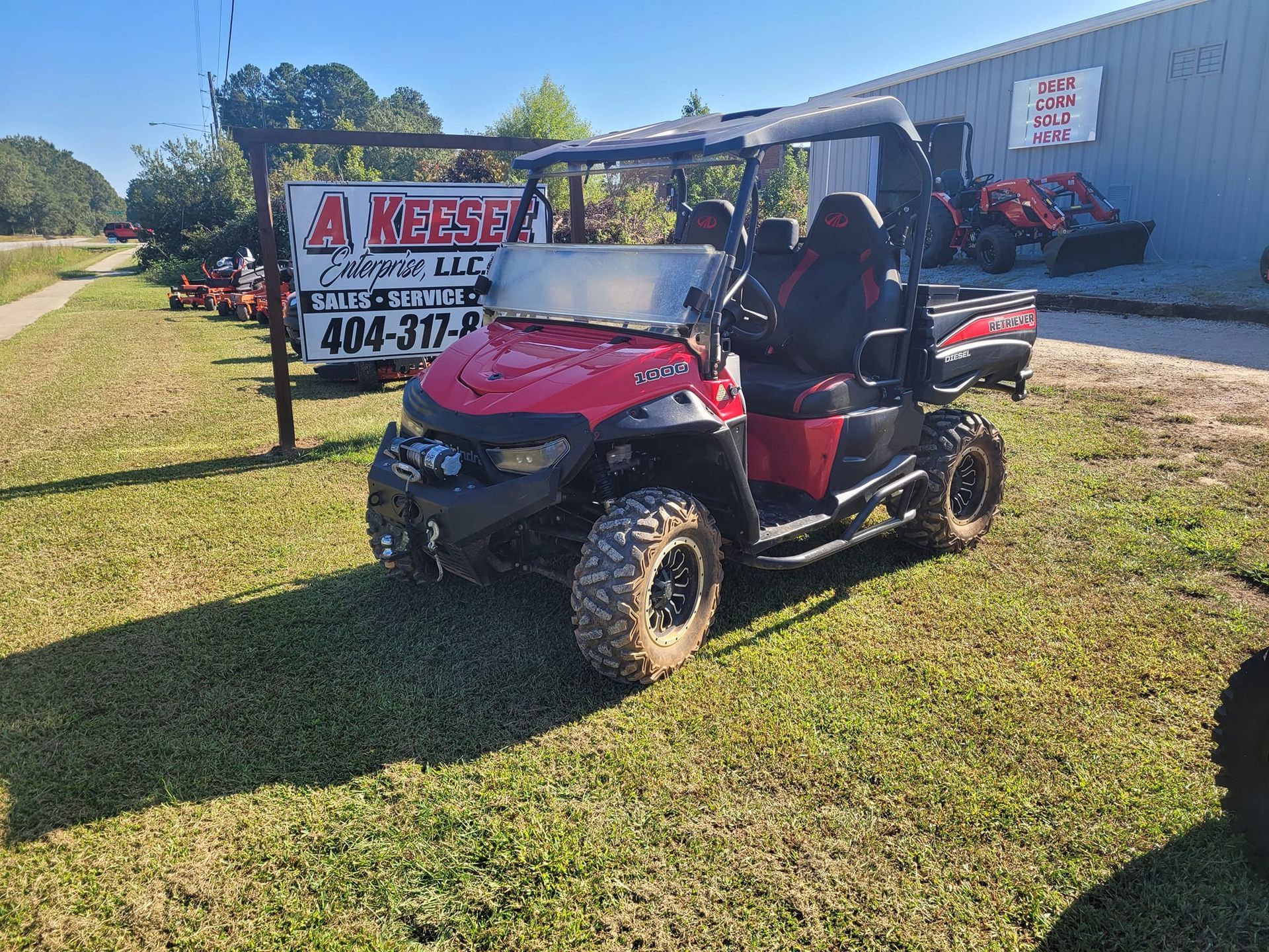 A red atv is parked in the grass in front of a building.