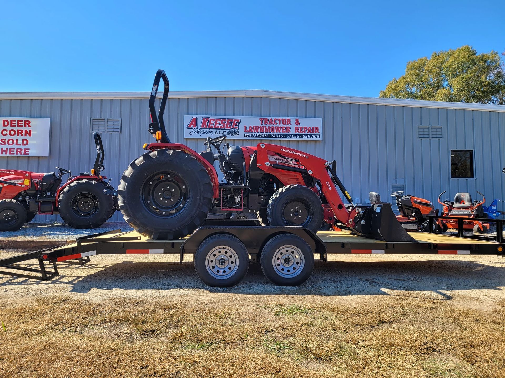 A red tractor is on a trailer in front of a building.