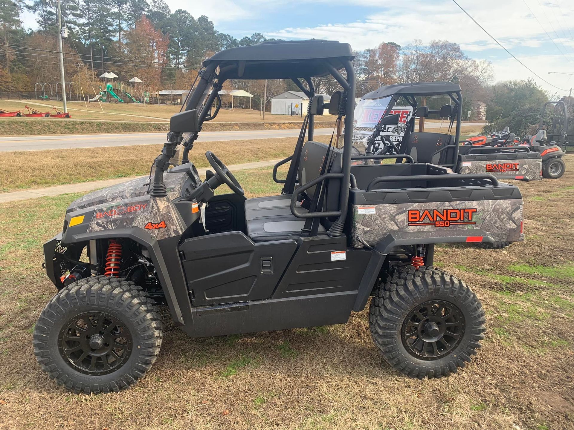 A camouflage atv is parked in the grass next to a sign.