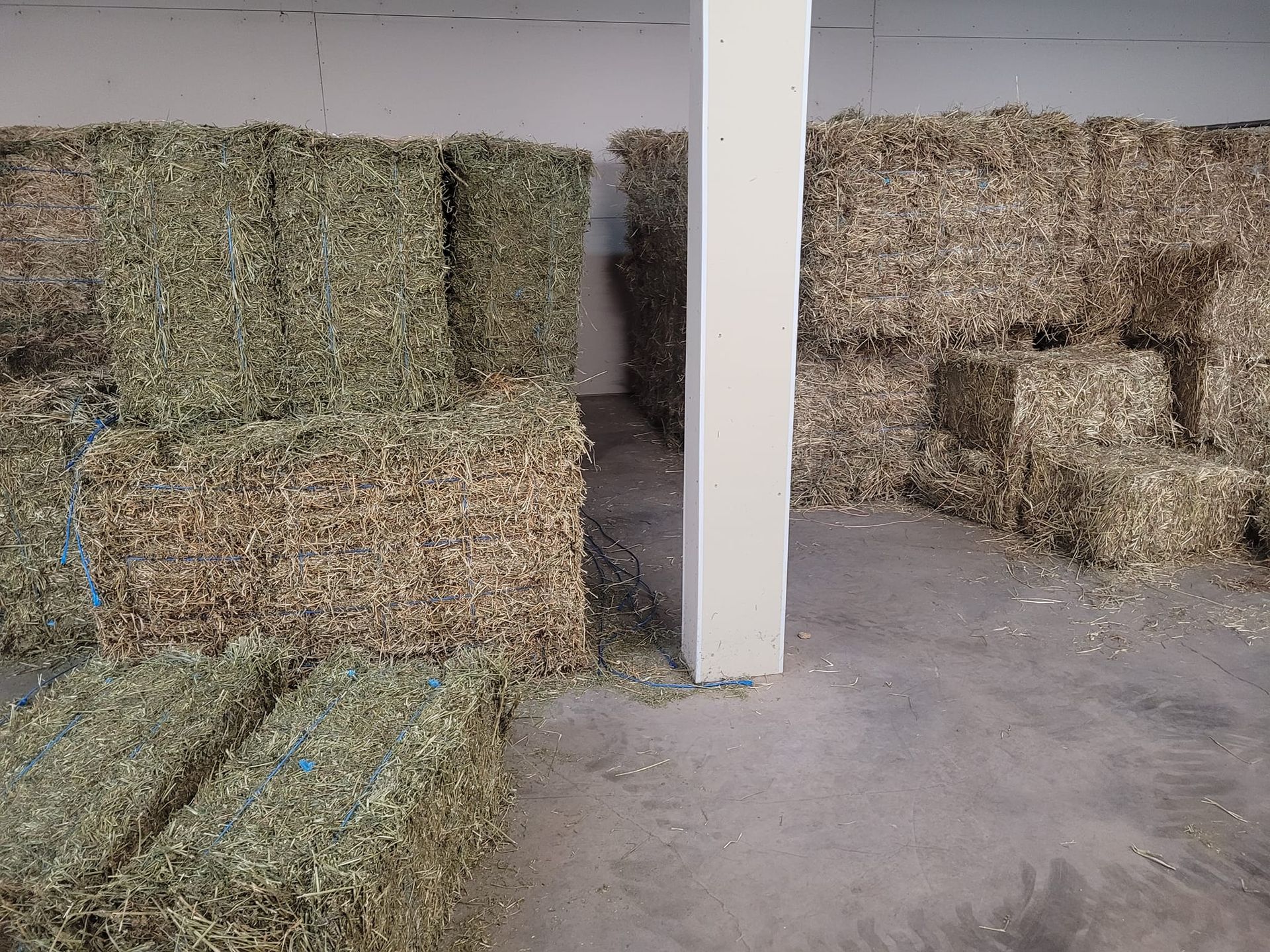 A bunch of hay bales are stacked on top of each other in a room