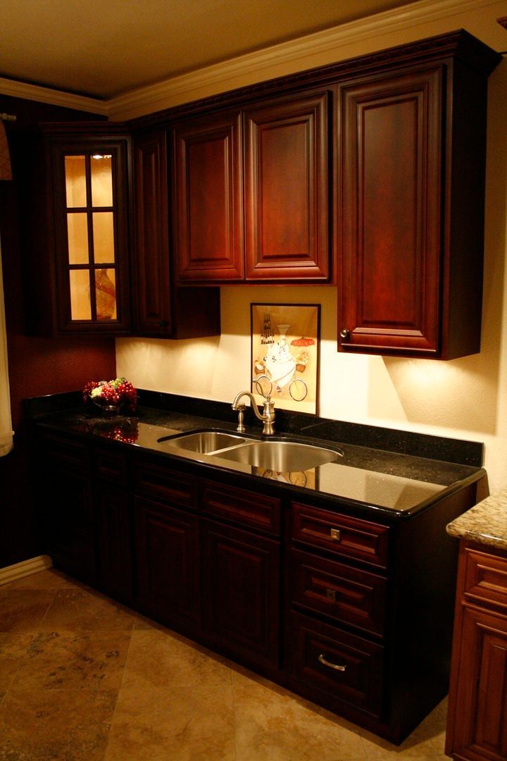 A kitchen with dark wood cabinets and a sink