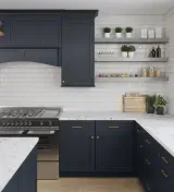 Modern kitchen with dark navy cabinets, white tile backsplash, open shelves, and a gas range.