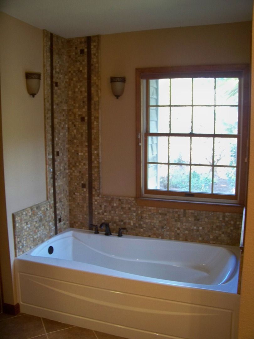 A bathtub in a bathroom next to a window
