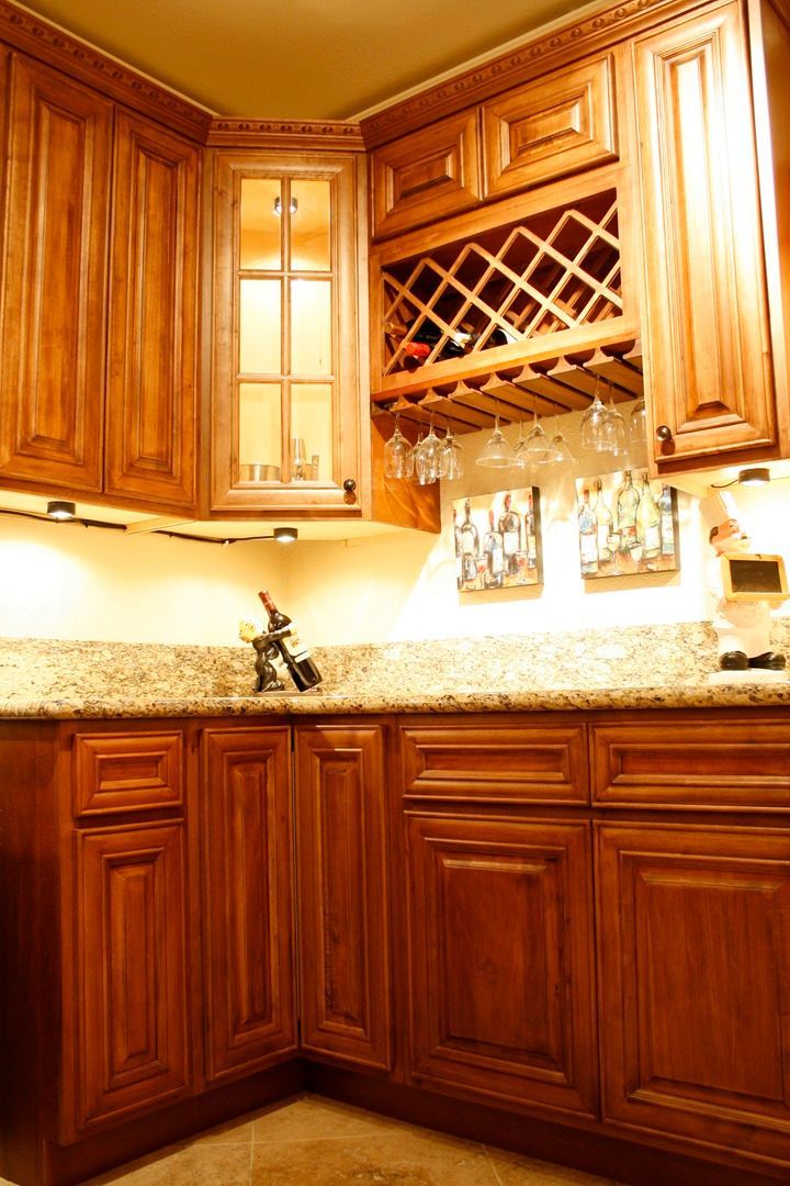 A kitchen with wooden cabinets and a wine rack above the counter.