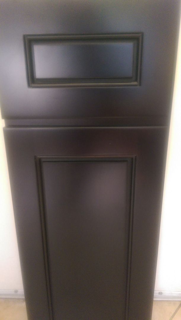 A black cabinet door is sitting on a tiled floor.