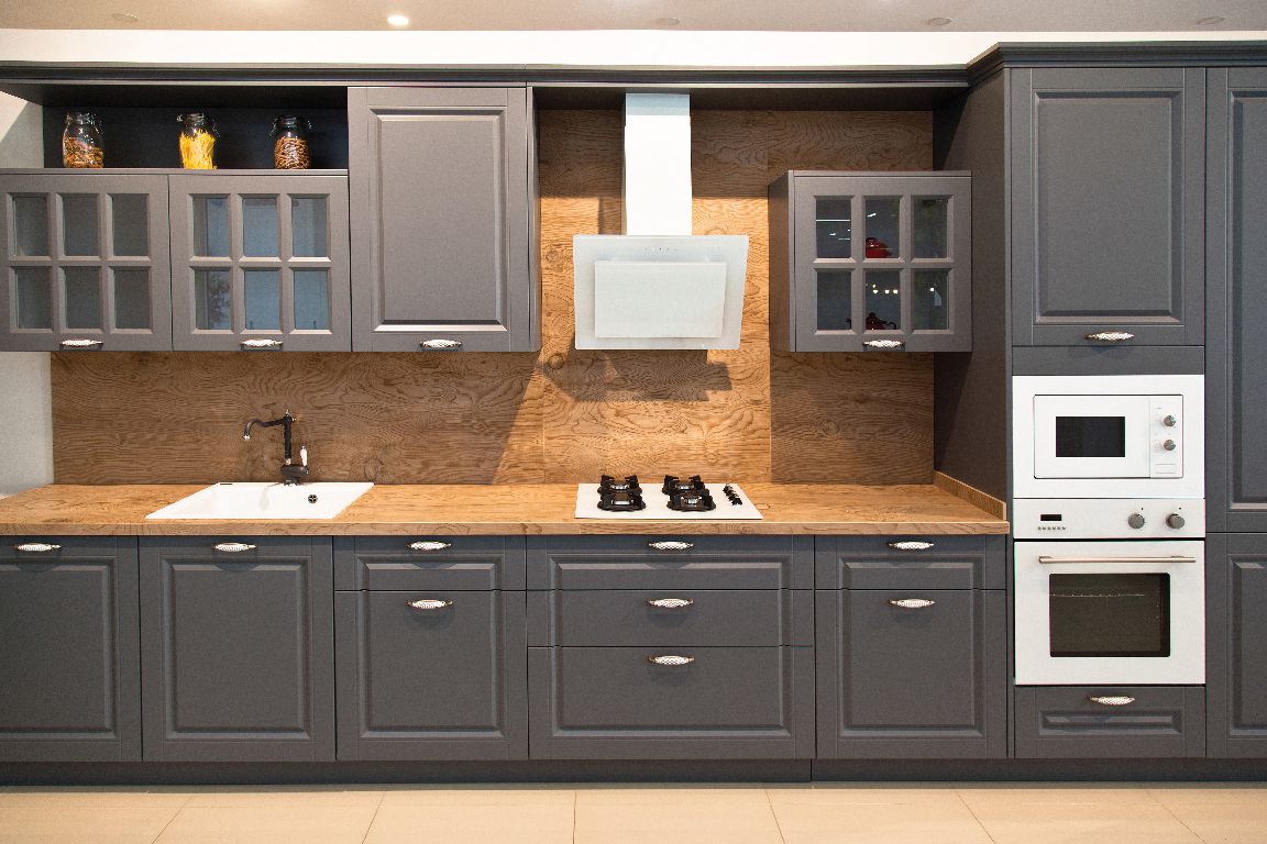 Modern kitchen with light wood cabinets, white countertops, and a central island.