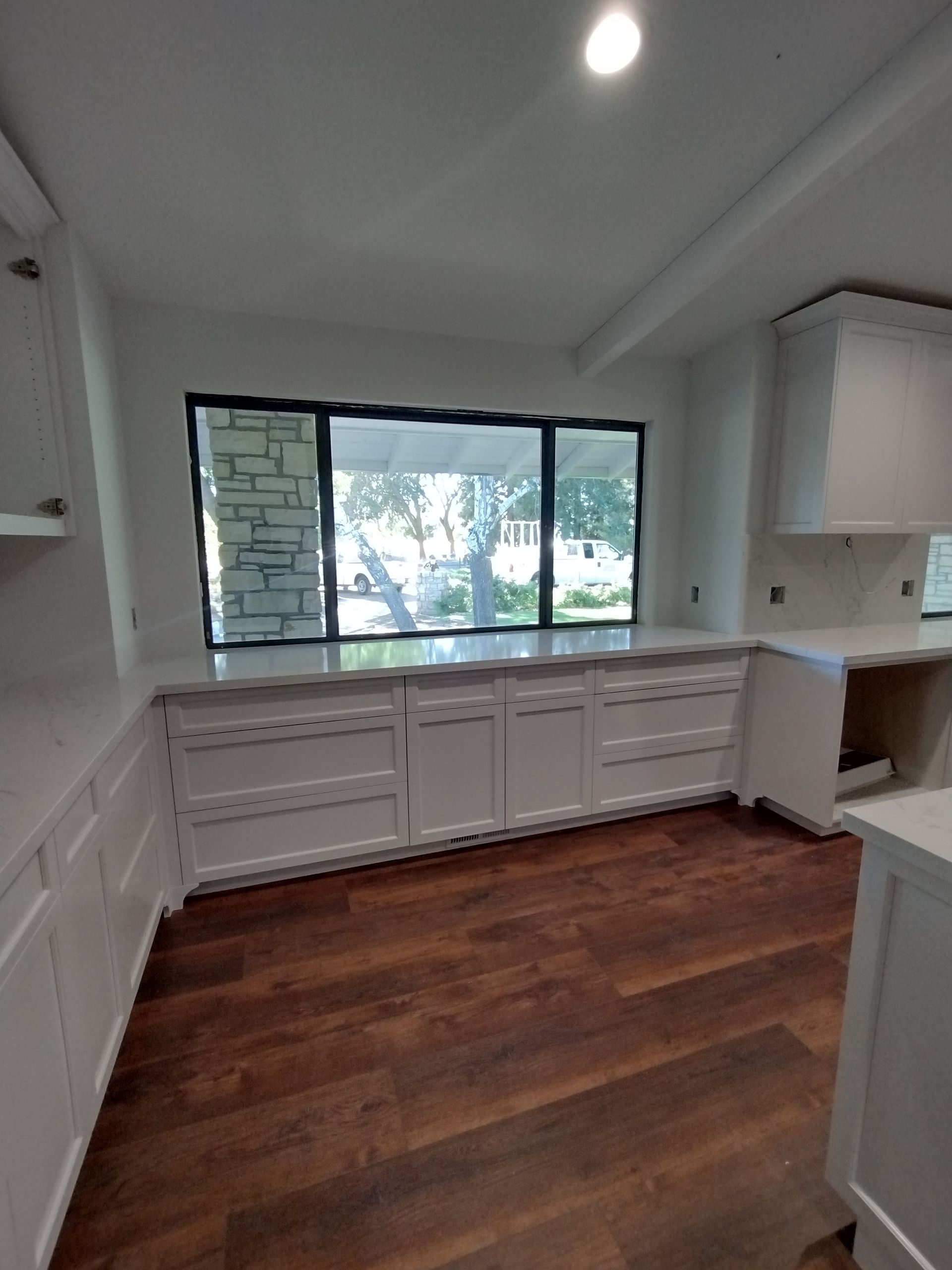 A kitchen with hardwood floors and white cabinets