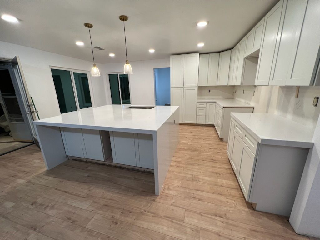 A kitchen with white cabinets and a large island in the middle.
