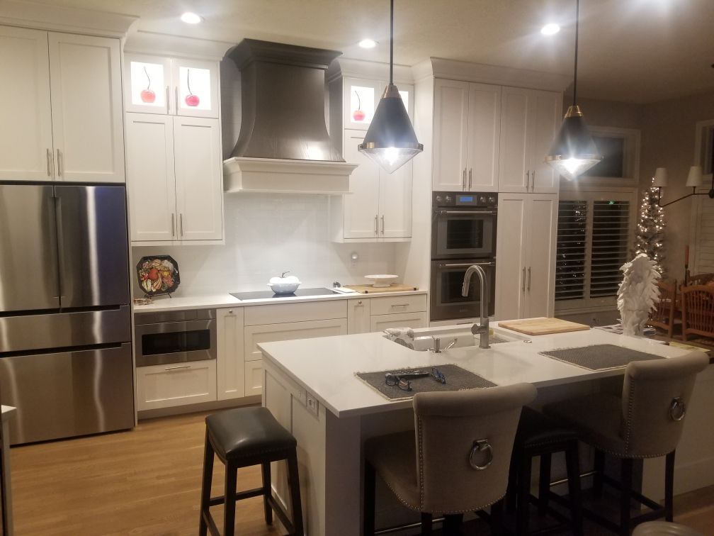 A kitchen with white cabinets , stainless steel appliances and a large island.