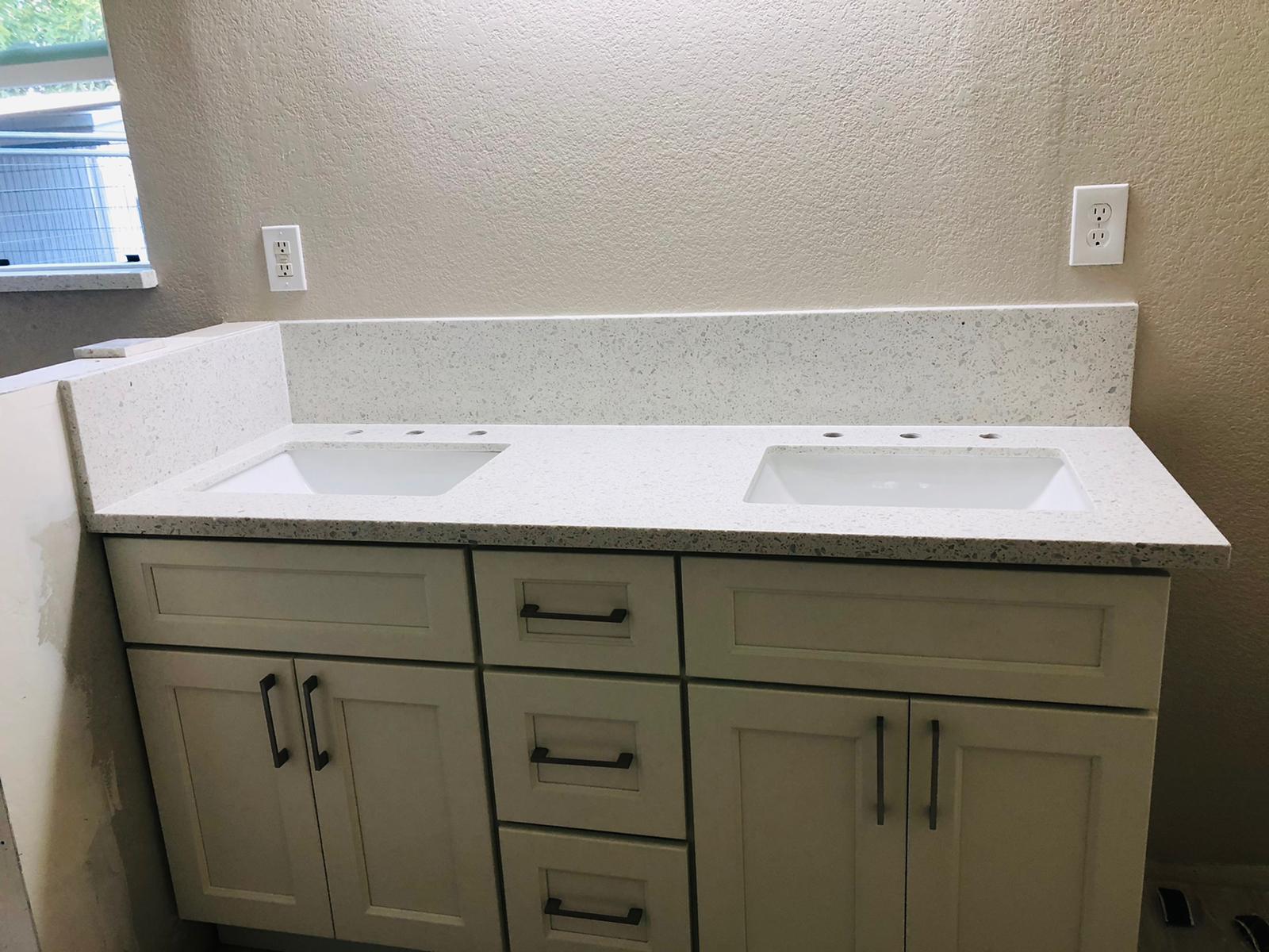 A bathroom vanity with two sinks and white cabinets