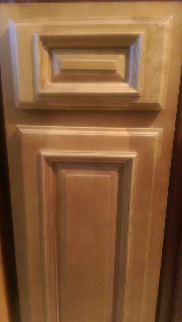 A close up of a maple glaze wooden cabinet door in a kitchen.