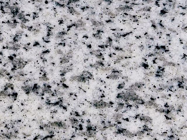 A close up of a white granite counter top with black spots