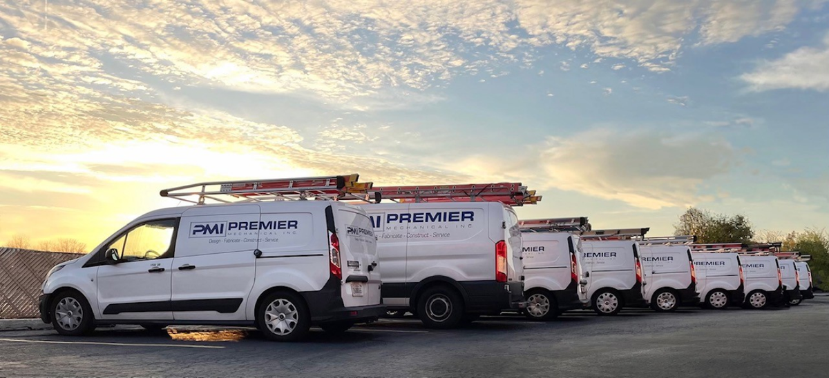 A row of white vans are parked in a parking lot.