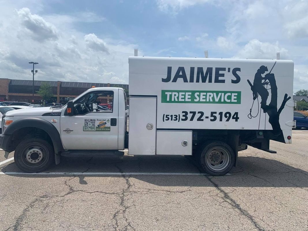 A white Jaime's Tree Service work truck parked in a parking lot with its business name and phone number on the side.