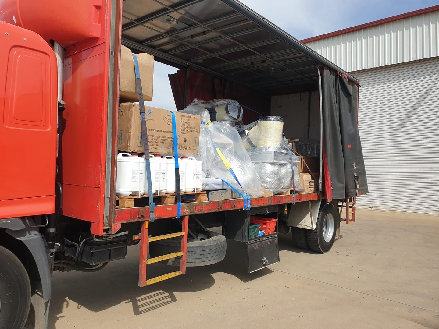Red Truck is Parked in Front of a Building Filled With Boxes - Turtle Couriers in Tamworth, NSW