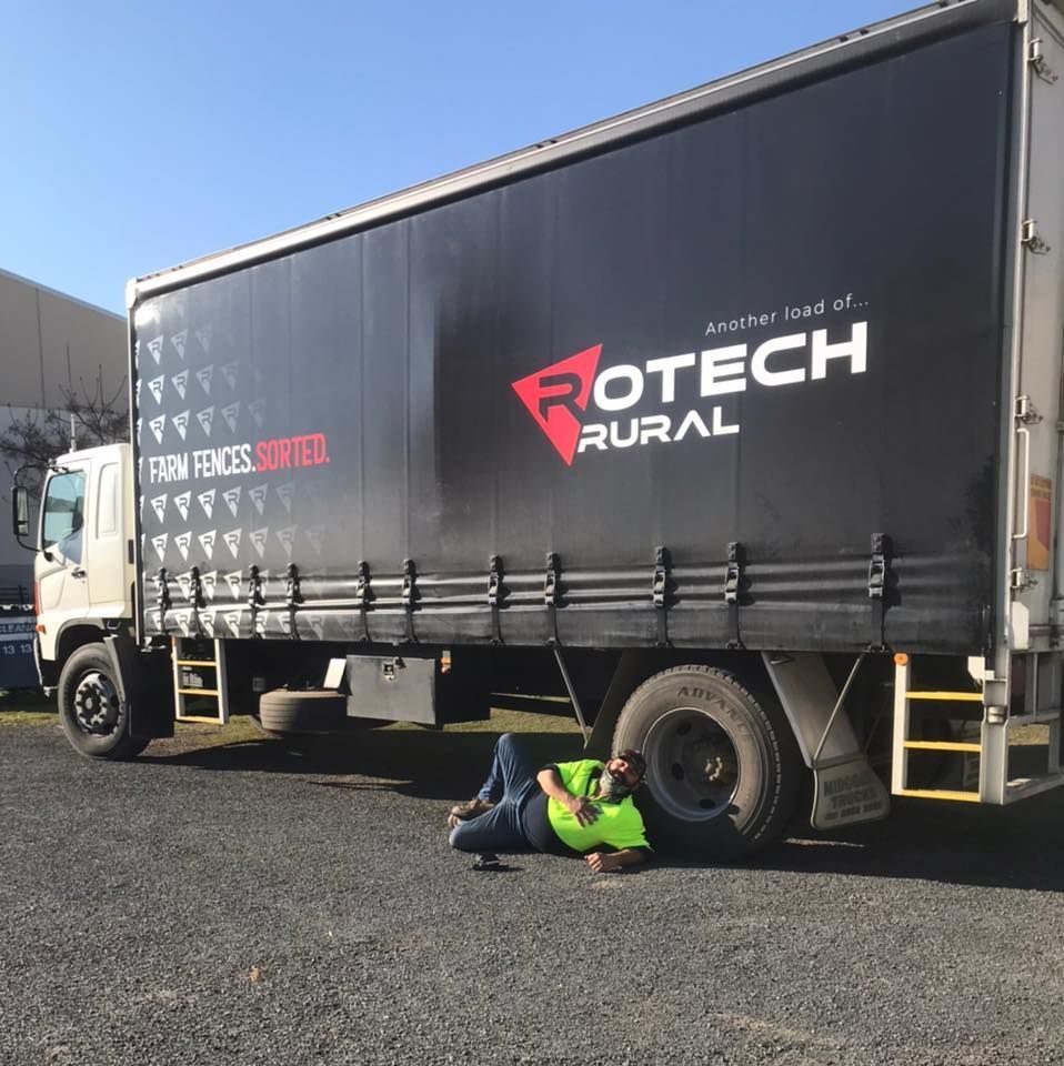 Man Laying on the Ground Next to a Rotech Rural Truck - Turtle Couriers in Tamworth, NSW
