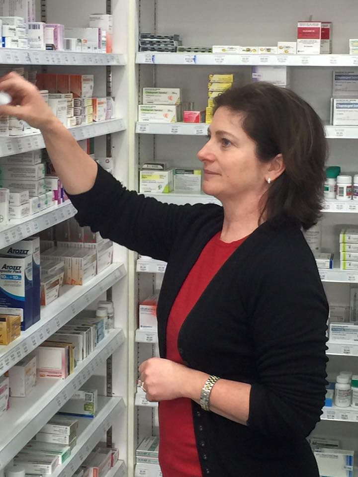 A woman in a red shirt is looking at a shelf of pills
