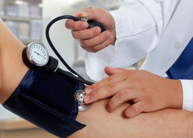 Healthcare professional measuring a patient's blood pressure with a sphygmomanometer.