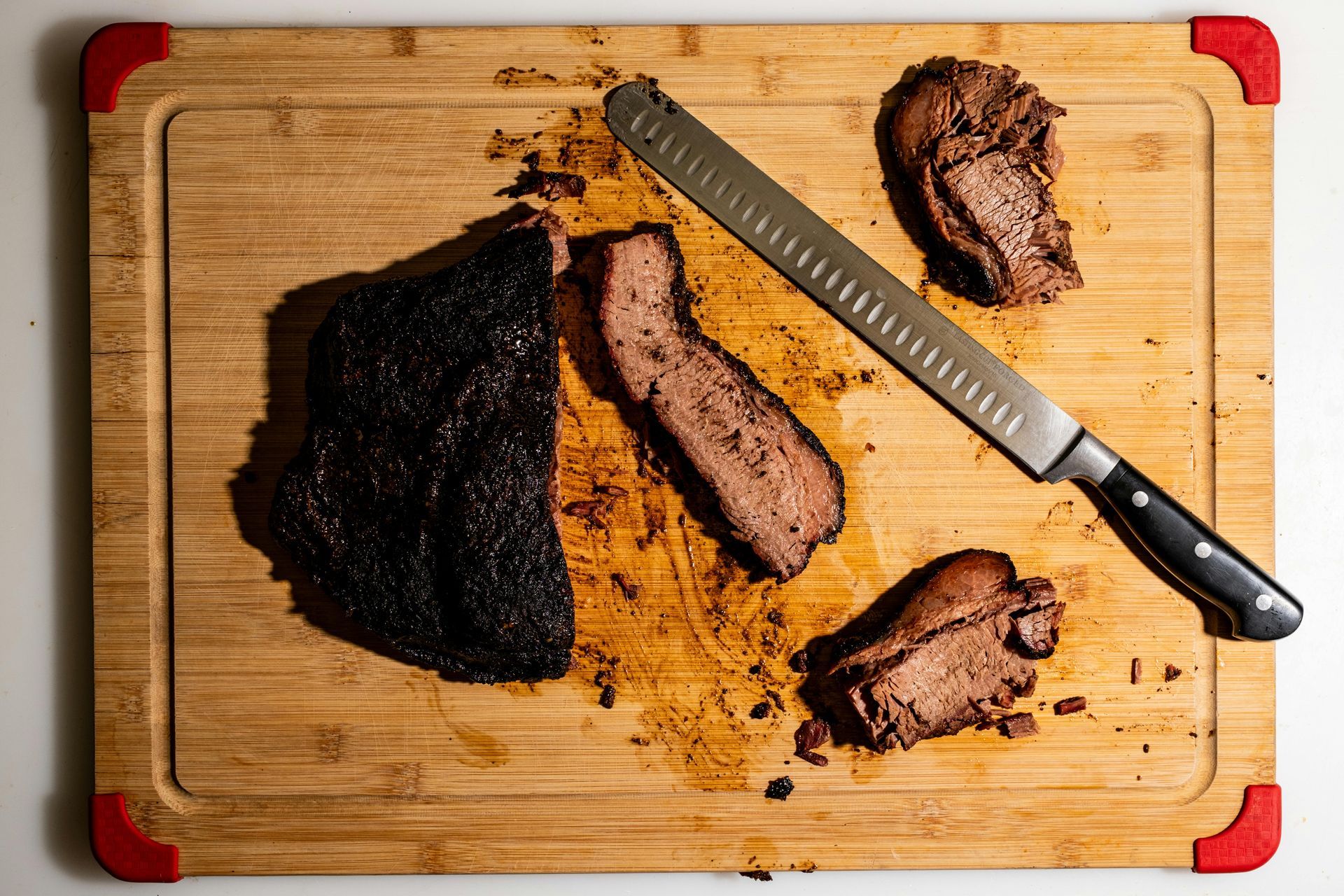 Sliced smoked brisket on a wooden cutting board with a knife.