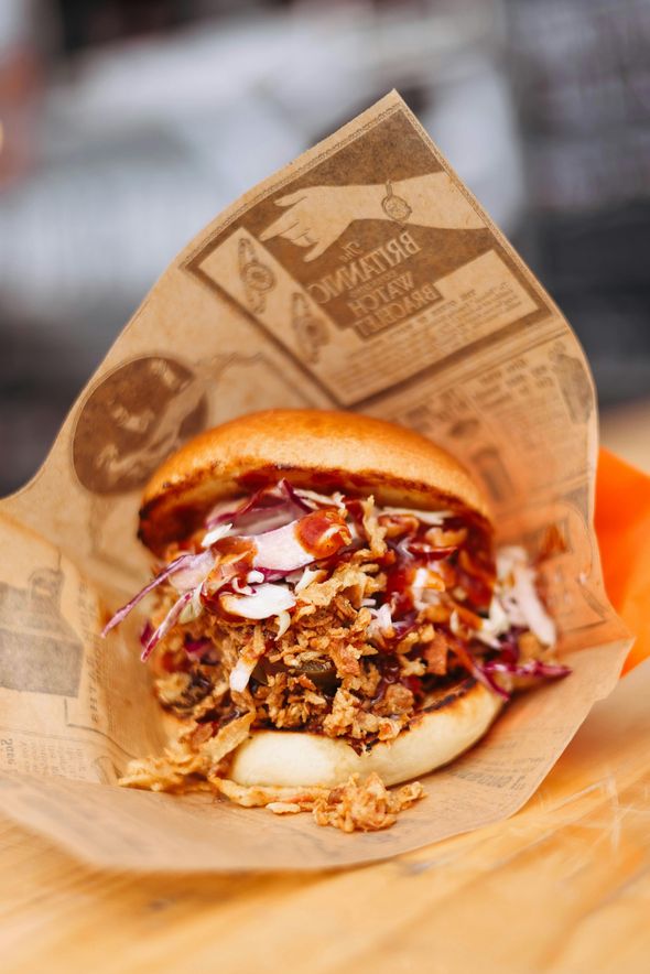 Pulled pork sandwich with coleslaw and sauce in brown paper.